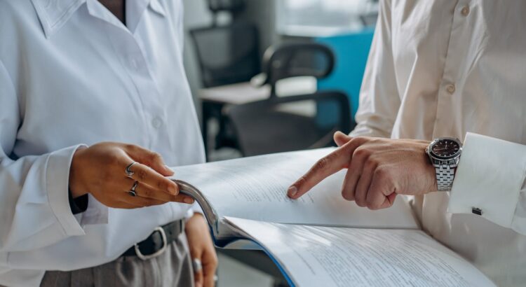 Colleagues Standing in White Long Sleeve Shirts Discussing and Reading a Financial Report