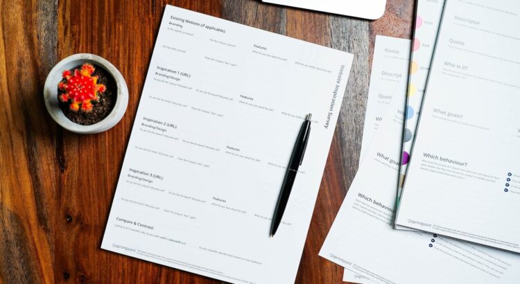 a wooden table topped with papers and a pen